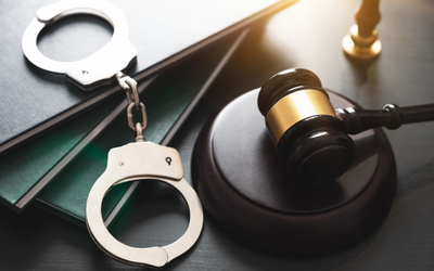 Judge's gavel on a desk with handcuffs on top of file folders