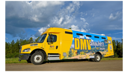 Yellow mobile DMV2GO RV camper truck parked by trees